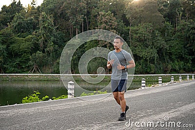 An athlete, strong Asian male runner in sportswear is running in a parl in the morning Stock Photo