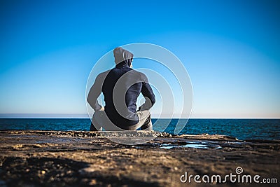 Athlete taking break sitting on rocks with sea horizon Stock Photo