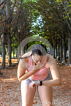 Athlete tired woman watching her smart watch in a park. Sporty young woman watching the clock in a park. Stock Photo