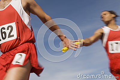 Athletes Passing Baton In Relay Race Stock Photo