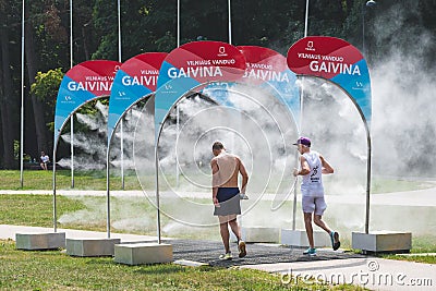 Athletes running through water mist to cool down during a competition Editorial Stock Photo