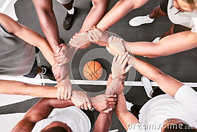 Athletes showing trust and standing united. Men expressing team spirit with their hands joined huddling at a basketball Stock Photo