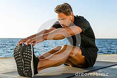 athletic adult man with wireless earphones stretching Stock Photo