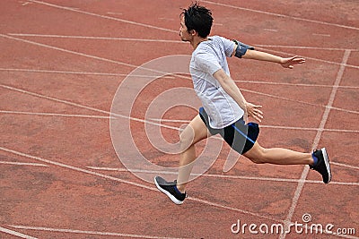 Athletic Asian runner sprinter crossing the finish line. Stock Photo