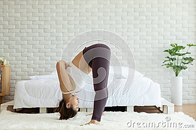 Athletic Asian woman practice yoga Spread foot stretching pose or Prasarita Padottanasana pose to meditation in bedroom Stock Photo