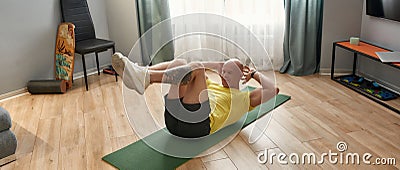 Athletic bald man doing crunches on fitness mat while working out in living room at home Stock Photo