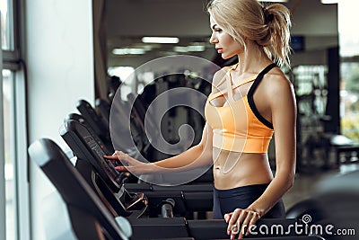 Athletic blond woman running on treadmill at gym. Stock Photo