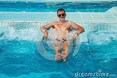 Athletic confident man relaxing in pool jacuzzi outdoor at spa resort enjoying luxury life. Success, healthy lifestyle, body care Stock Photo