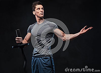 Athletic male holds barbell over grey background. Stock Photo