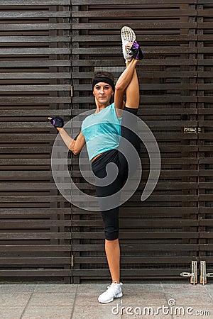 Athletic flexible young woman doing standing split exercise on the city street Stock Photo