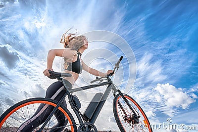 Athletic girl with hair flying in the wind leading electric bike Stock Photo