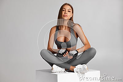 athletic girl sitting. Beautiful fitness woman, isolated on the gray Stock Photo