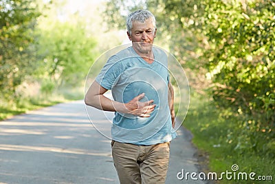 Athletic handsome senior male covers long distnace running, has pain in stomach, gets ready for marathon between elederly people, Stock Photo