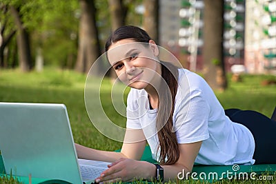Athletic healthy girl in a white t shirt working on a computer in nature and looking into the frame Stock Photo