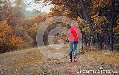 Athletic jogger in a black runs on the colorful yellow autumnal Stock Photo