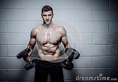 Athletic man doing exercises with dumbbells in The Gym's Stock Photo