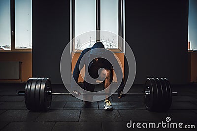 Athletic man in jacket with a hood waiting and preparing before lifting heavy barbell. fitness, sport, training, gym and lifestyle Stock Photo