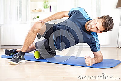 Athletic Man in Side Planking Using Foam Roller Stock Photo