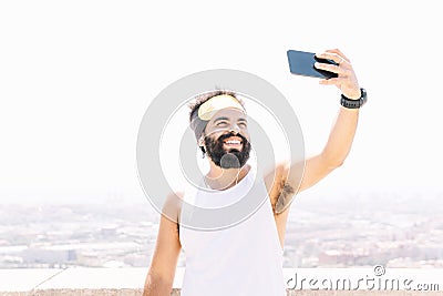 Athletic man taking selfie photo on the hill over the city with phone Stock Photo