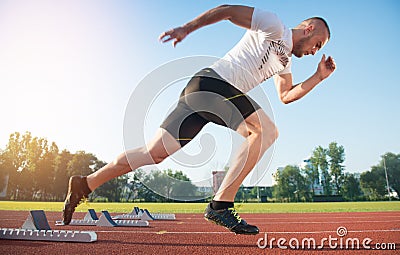 Athletic man on track starting to run. Healthy fitness concept with active lifestyle. Stock Photo