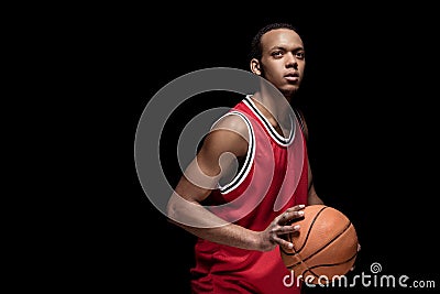 Athletic man in uniform playing basketball on black Stock Photo