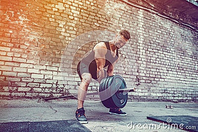 Athletic man working out with a barbell. Strength and motivation. Exercise for the muscles of the back Stock Photo