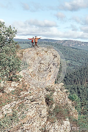 Athletic mature couple stands on a high rock above the white river against the background of the Ural mountains Stock Photo