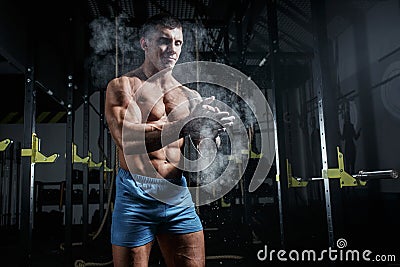 Athletic pumped man bodybuilder slaps magnesia in gym Stock Photo