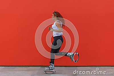 Athletic redhead woman running while wearing Kangoo Jumps boots Stock Photo