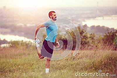 Athletic runner doing stretching exercise Stock Photo