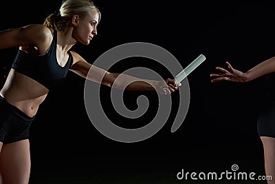 Athletic runners passing baton in relay race Stock Photo