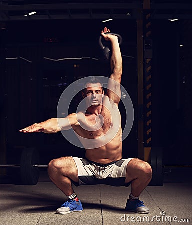 Athletic strong man doing the exercises with kettlebell on dark Stock Photo
