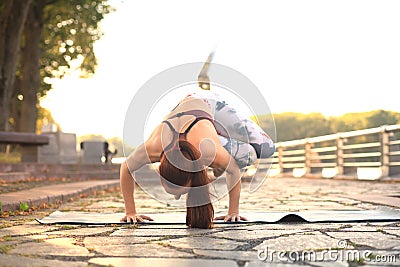 Athletic strong woman practicing difficult yoga pose outdoors Stock Photo