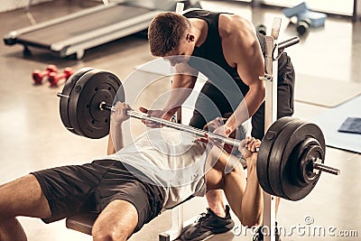 athletic trainer helping sportsman lifting barbell with heavy weight plates Stock Photo