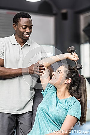 Athletic woman lifting weights helped by trainer Stock Photo