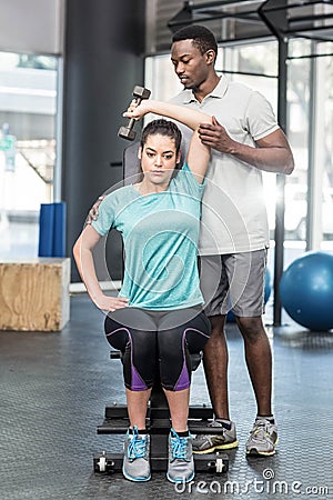 Athletic woman lifting weights helped by trainer Stock Photo