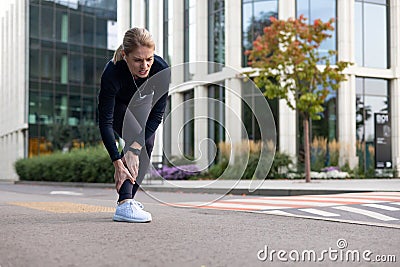 Female runner experiencing leg pain during outdoor training in the city Stock Photo