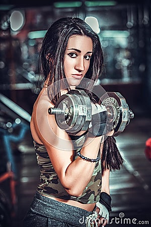 Athletic woman pumping up muscules with dumbbells Stock Photo