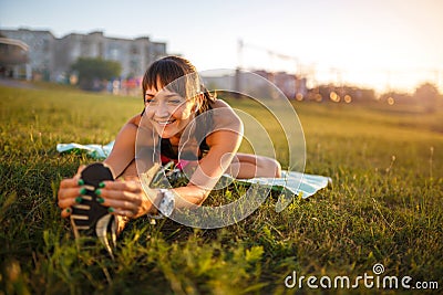 Athletic woman stretching her hamstring, legs exercise training fitness before workout outside with headphones listening music. Stock Photo