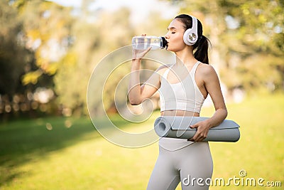 An athletic woman in stylish sportswear hydrates while drinking from a water bottle Stock Photo