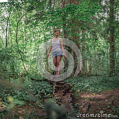 Athletic woman in a tank top and shorts in a forest among green trees Stock Photo