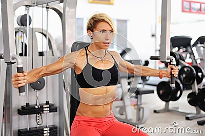 Athletic women training chest on a simulator at gym Stock Photo