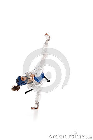 Athletic young girl in dobok and blue helmet practicing, training taekwondo isolated over white background Stock Photo