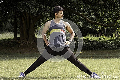 Athletic young man streching his legs in the sports ground. Healthy lifestyle , fitness and sports concept. Stock Photo