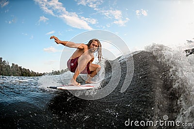 Athletic young man wakesurfing down the river waves Stock Photo