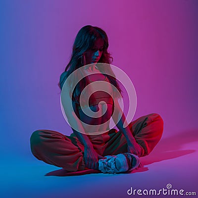 Athletic young woman in a vintage top in fashion pants doing yoga in a room with a multi-colored color in the style disco. Stock Photo