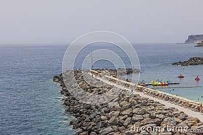 Atlantic Ocean featuring a stone revetment designed to reduce waves, providing a designated area for people to swim and relax. Editorial Stock Photo