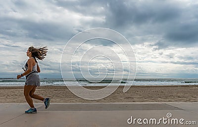 Atlethic woman running in front of the beach Editorial Stock Photo