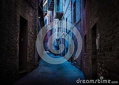 A dark and narrow, back alley painted with blue and magenta light taken in Recanati, Macerata, Italy Stock Photo