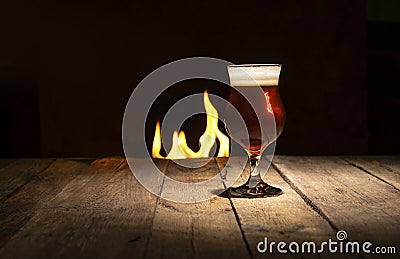 Atmospheric evening in a pub. Beer glass on a dark wooden background with fire place Stock Photo